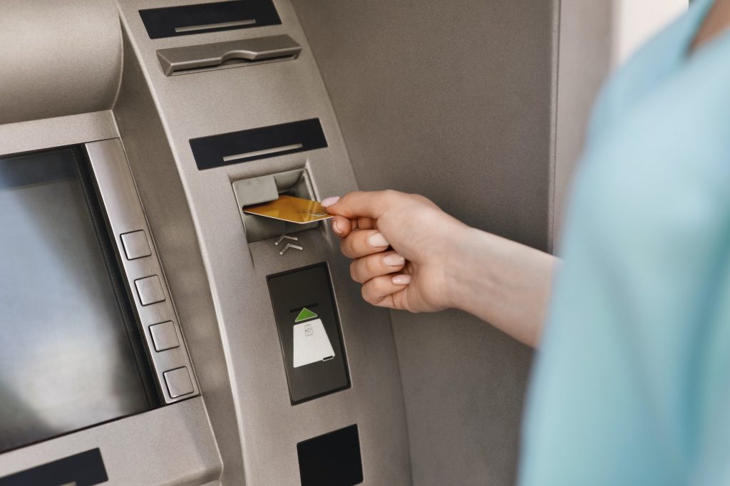 Close up of female hand inserting credit card in the ATM machine Wages Protection System Abu Dhabi
